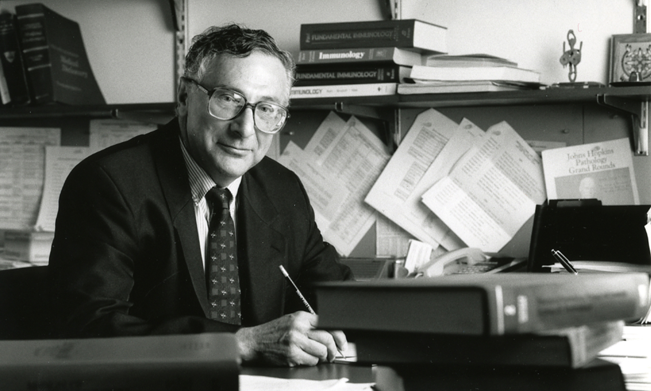 Noel R Rose sitting at his desk