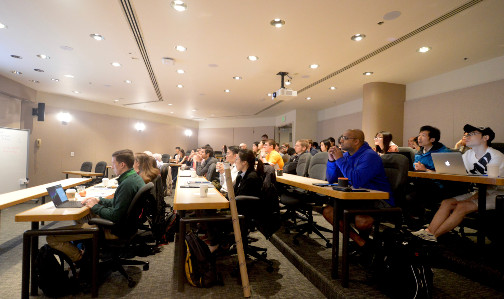 An auditorium filled with people in seats at long, narrow tables