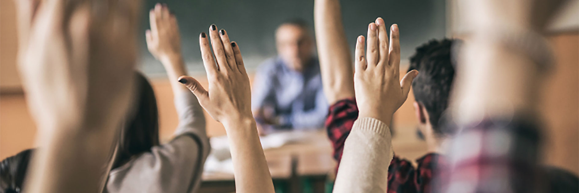 students in classroom raising hands