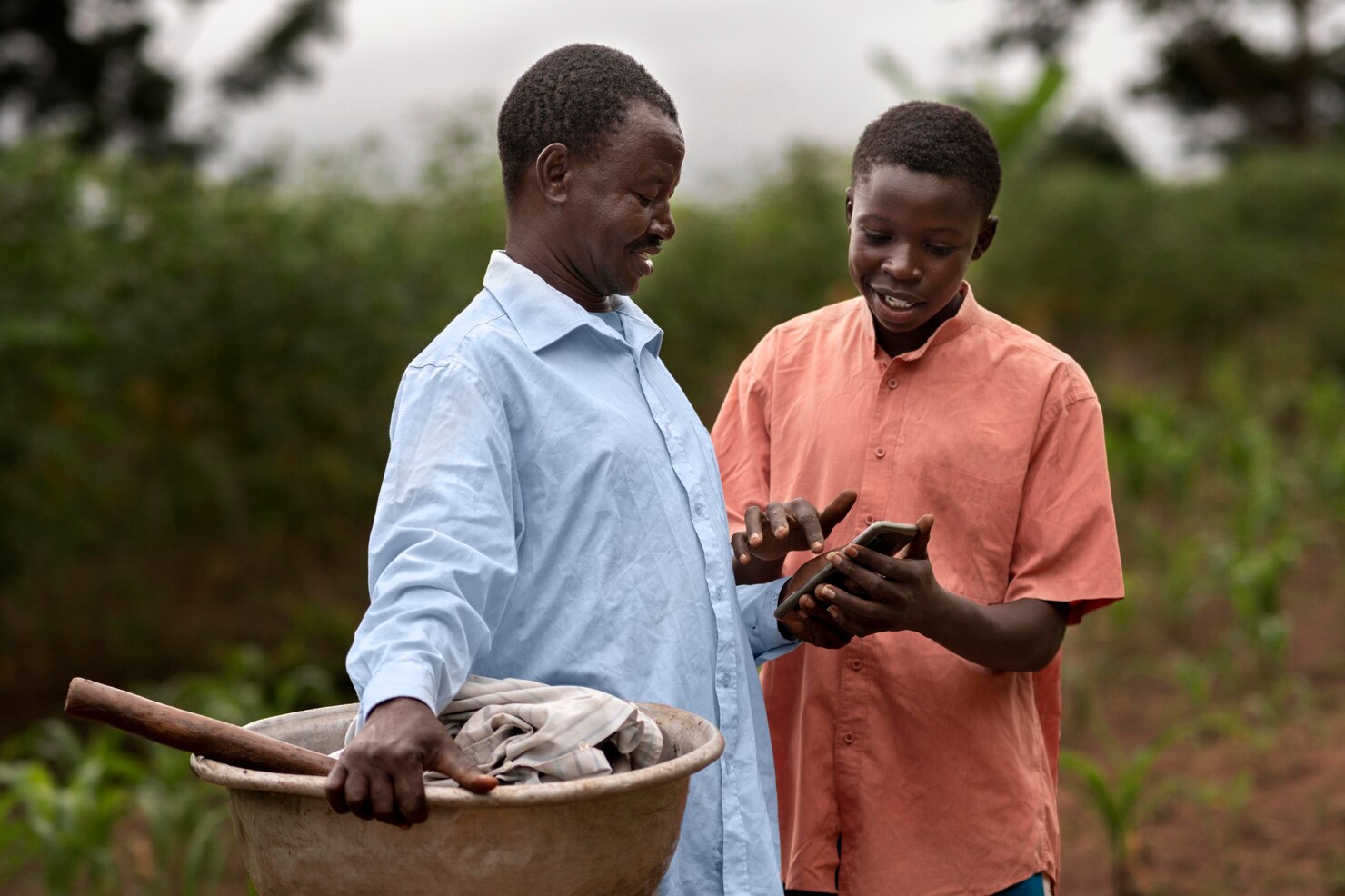 Youth demonstrating phone use to older adult on a rural farm land