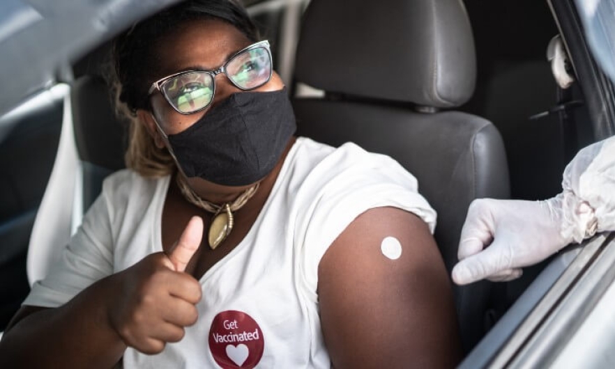 A woman gives a thumbs up after receiving a COVID-19 vaccine