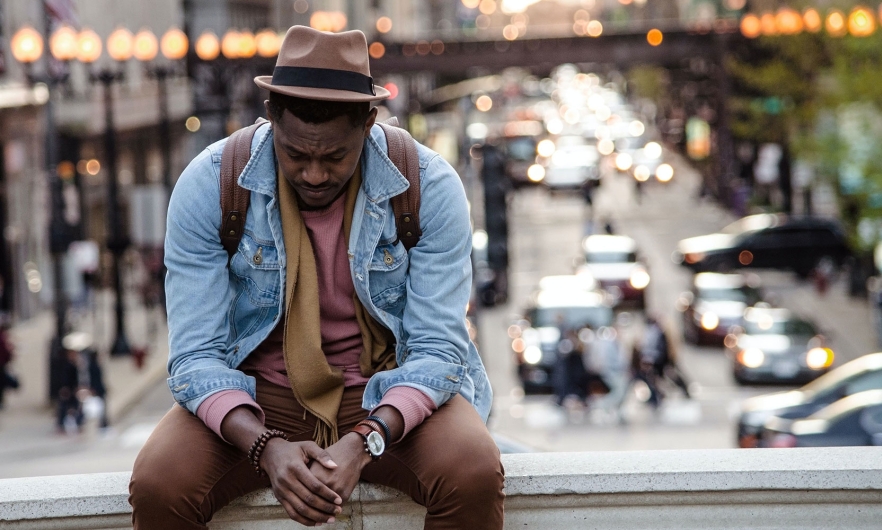 african american man looking down with cityscape in the background