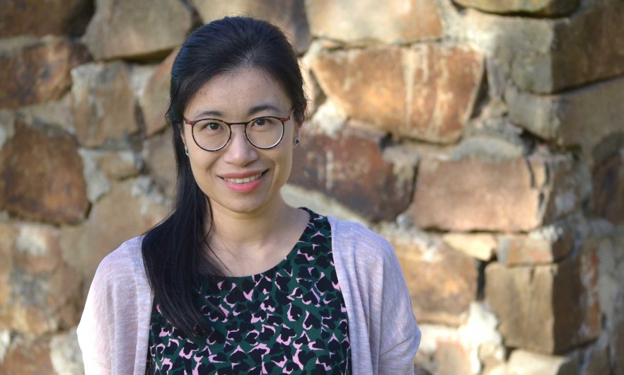 Danfeng Cai, smiling in front of a rock wall