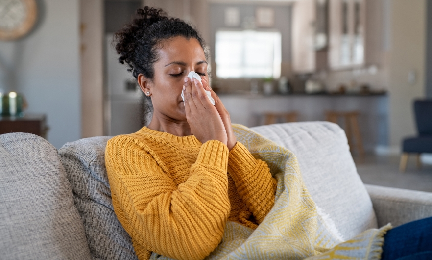 woman sitting on the couch blowing her nose