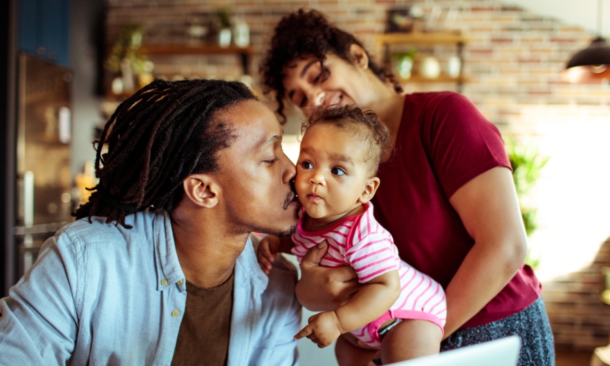 Young black father holding infant kissing her