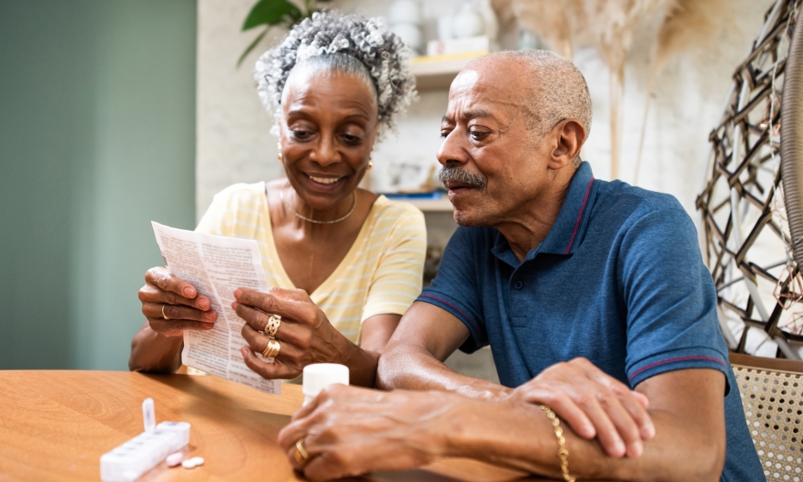 Two senior citizens sit at a table reviewing a Medicare form.