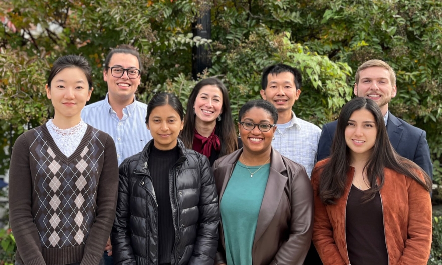 Eight people standing together outdoors, smiling