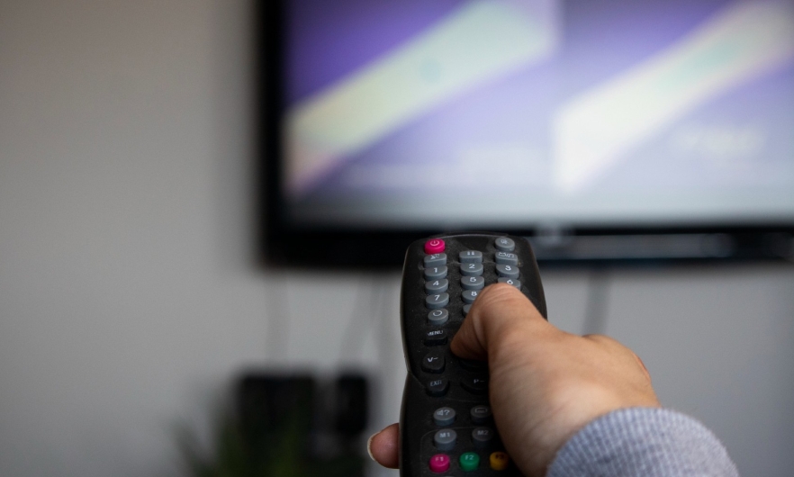 Person aiming remote control at television