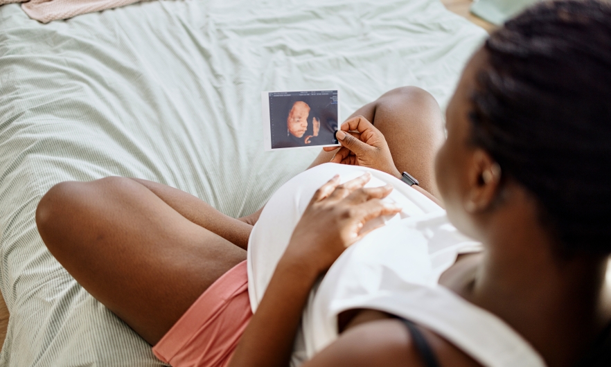 Black pregnant woman holding a sonogram