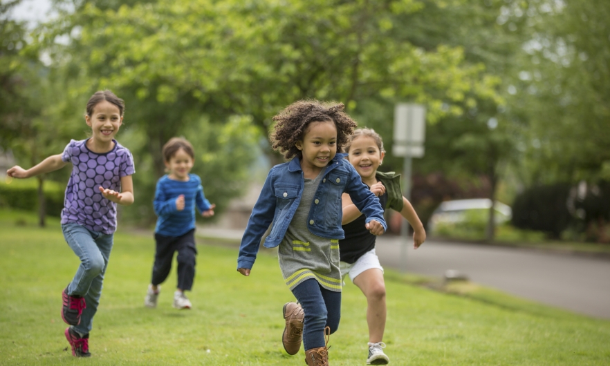 Four kids running and playing on the grass