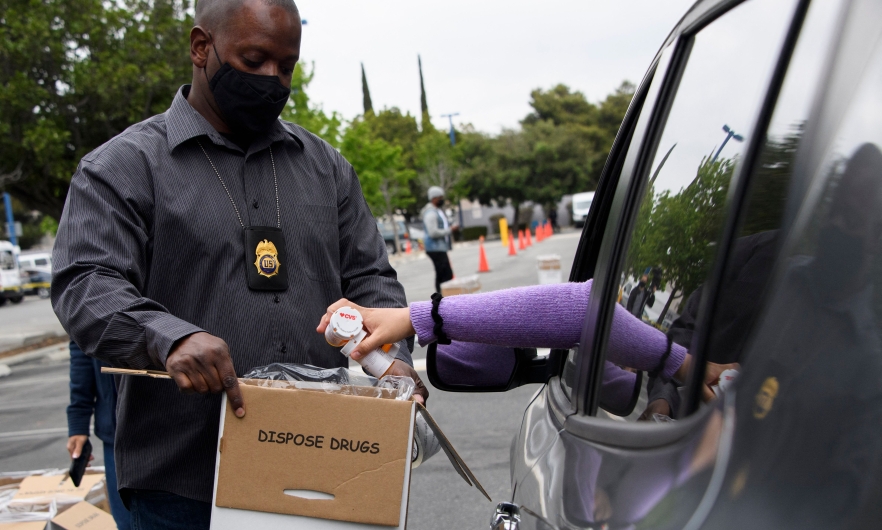 Mike Davis, associate special agent in charge for the Los Angeles division of the Drug Enforcement Administration, holds a container as a driver drops off bottles of prescription drugs to be boxed for disposal during the 20th National Prescription Drug Take Back Day at Watts Healthcare on April 24, 2021.