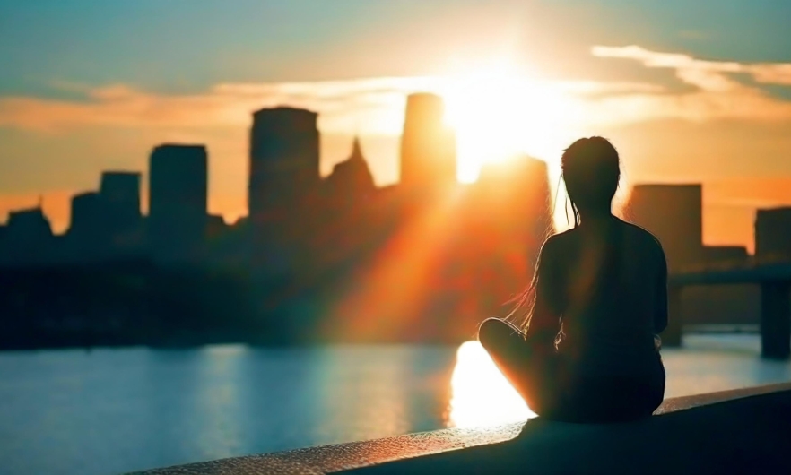 A woman sitting on the water at sunrise