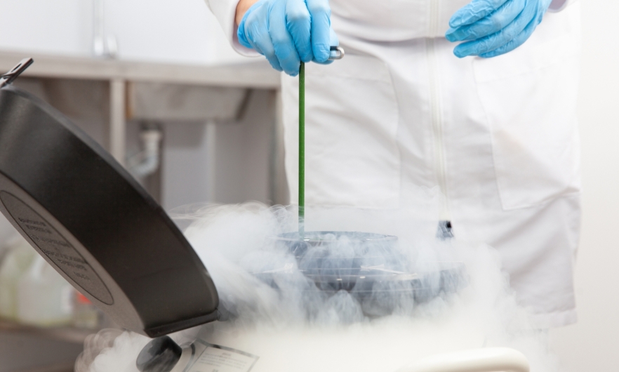 Lab tech removes sample from cryogenic tank