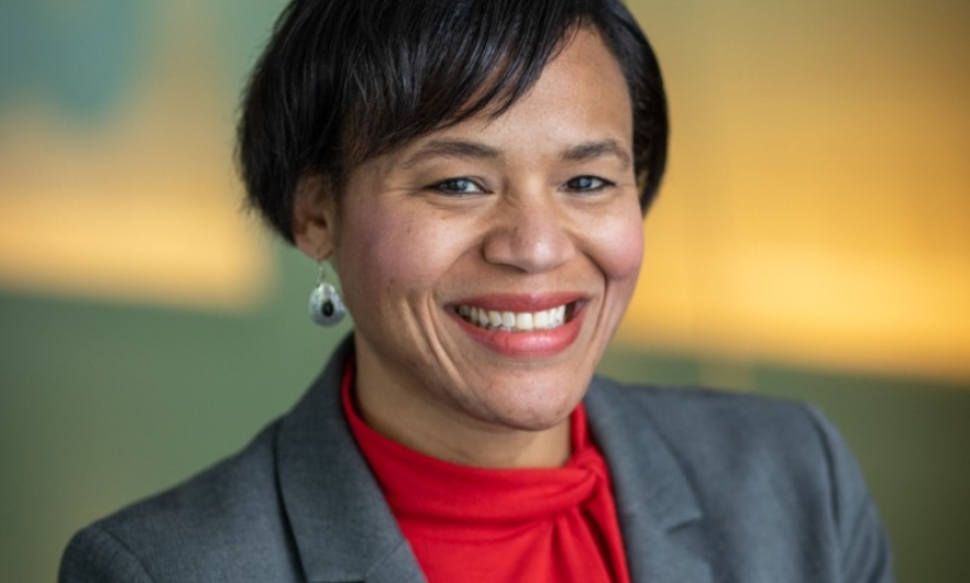 A headshot of department chair Keshia Pollack Porter. She smiles at the camera while wearing a red blouse under her grey suit jacket.