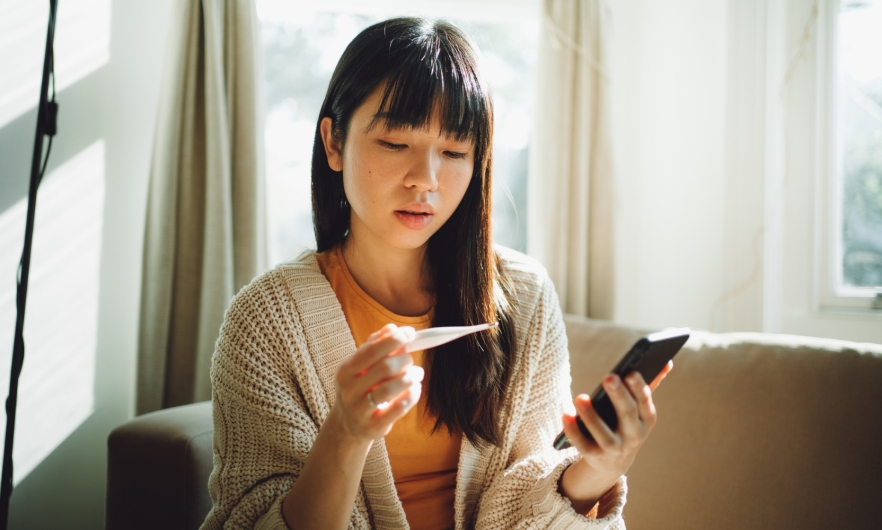 Woman in sunny living room reads thermometer results