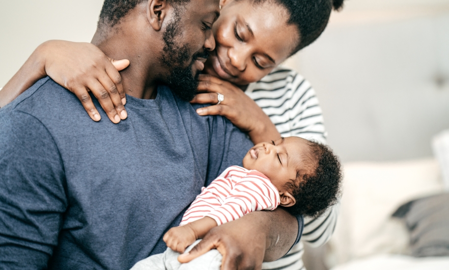 Two young parents hold their infant