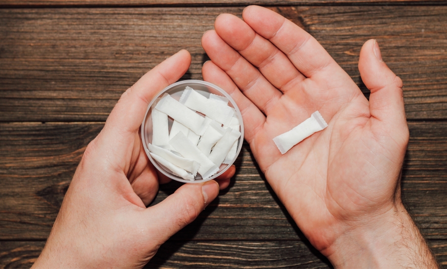 A person holds a container of nicotine pouches