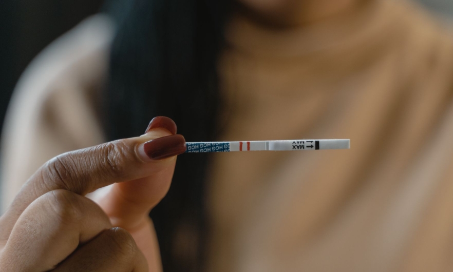 A hand holding a fentanyl test strip. Two short red lines run down the middle of the test strip.