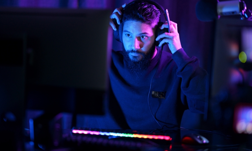 Man sitting at computer puts on gaming headset