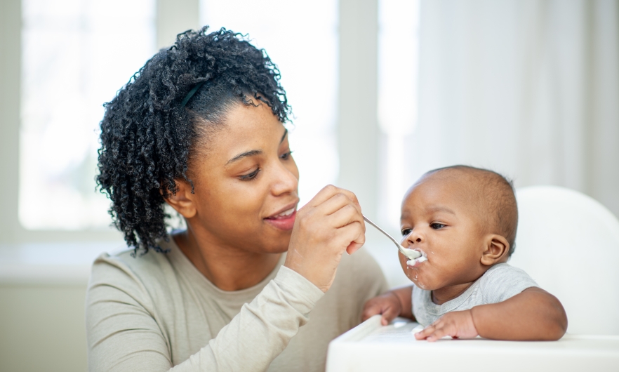 A baby boy in his highchair as his Mother feeds him A baby boy in his highchair as his Mother feeds him