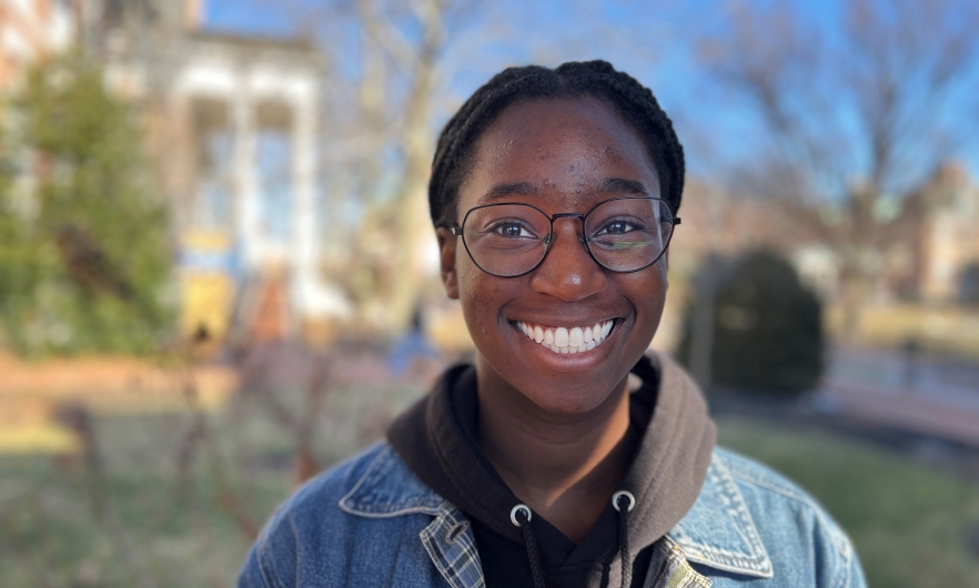Head shot of a young black woman with buildings and trees in the background