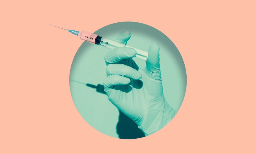 A doctor's gloved hand holding vaccine syringe placed inside a round hole of teal, background is salmon pink