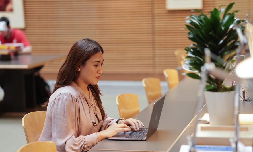 Student working at a laptop in the Bloomberg School reading room 