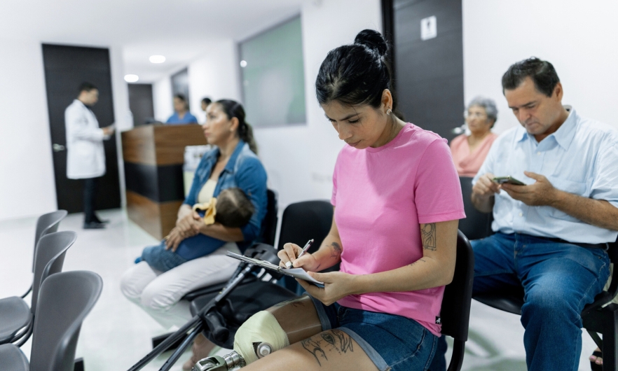 doctor's office waiting room A woman with a prosthetic leg fills out forms in the waiting room of a medical office. A mother and baby, an older woman, and a middle-aged man also sit waiting.