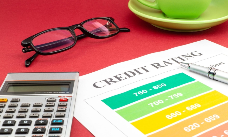 A calculator, pair of glasses, and paper that says credit rating are placed side by side