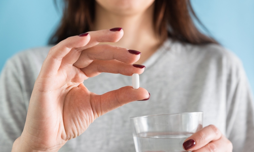 woman holding a pill - face not shown