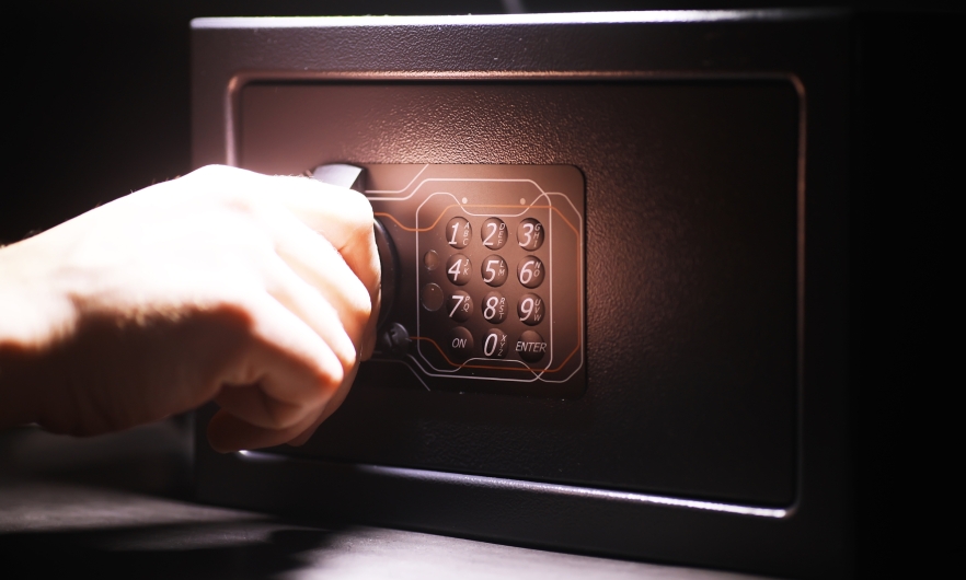 steel safe with keypad Hand on the handle of a black steel safe with a keypad.