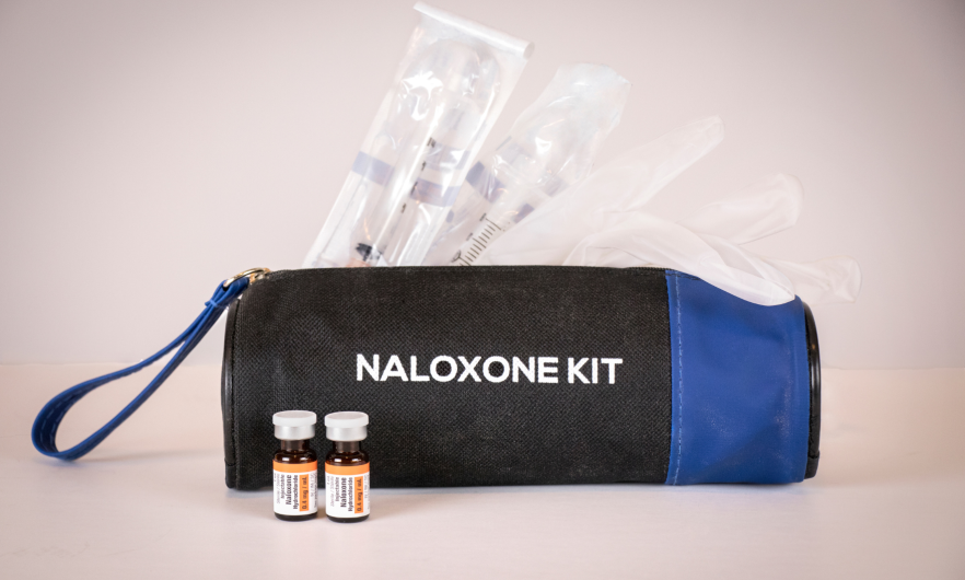 A bag labeled Naloxone Kit with syringes poking out of the top
