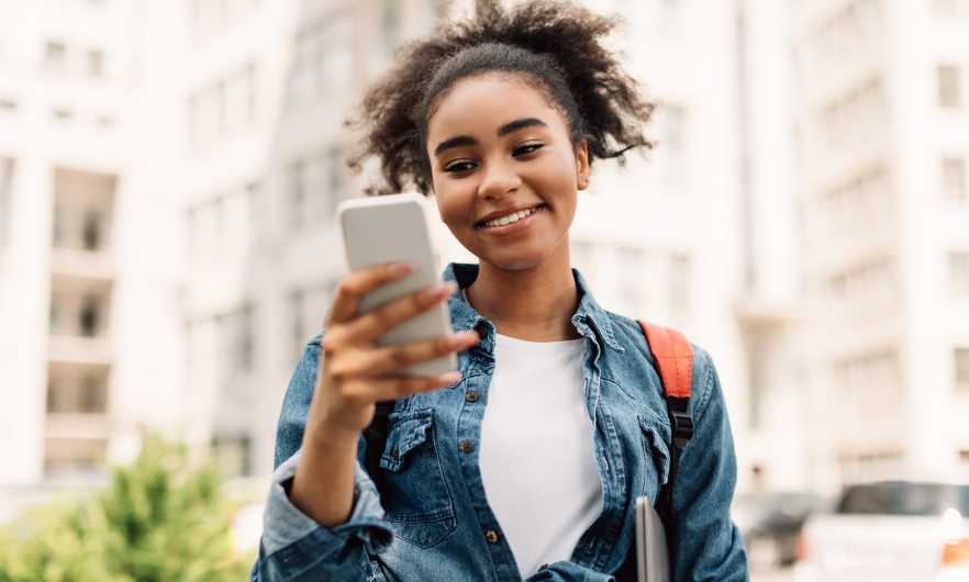 Teenager using smartphone Teenager smiling while holding smartphone outside