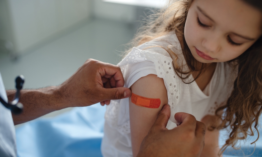 A doctor places a bandaid on the arm of a girl who has just received a vaccine.