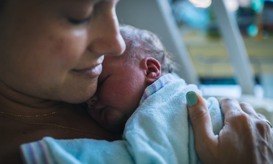 mother with newborn Closeup of mother holding newborn to her chest in hospital bed