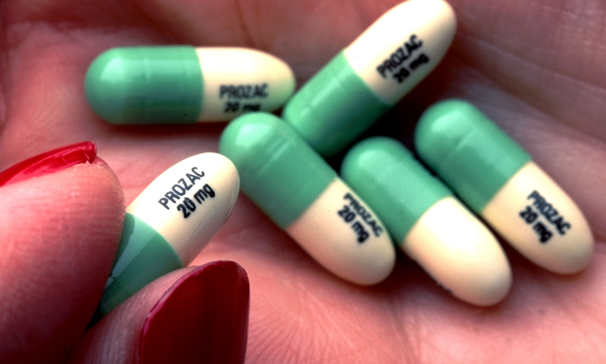 A person holds Prozac tablets in their palm.