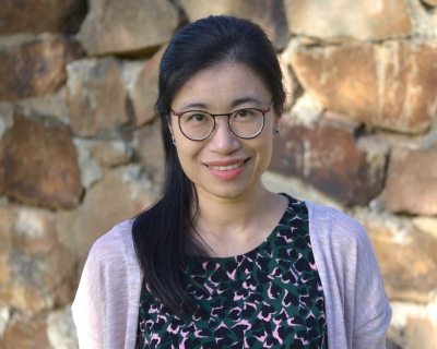 Danfeng Cai, smiling in front of a rock wall