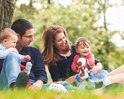 Young family sitting by a tree