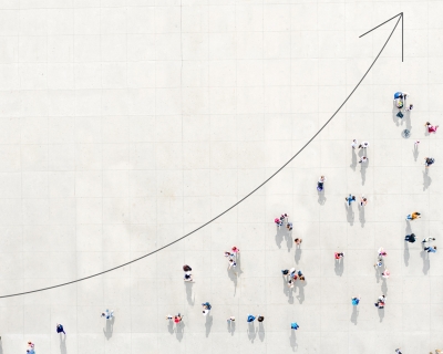 Aerial view of people on a graph beneath an arrow indicating an upward spike