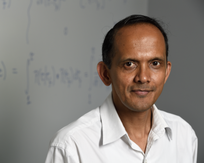 man smiling standing in front of chalkboard with mathematical equations