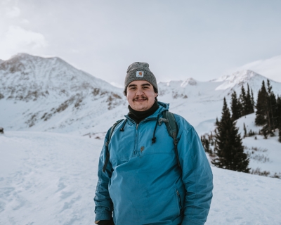 young man in teal coat in snowy landscape