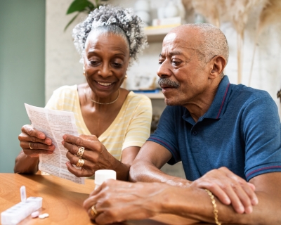 Two senior citizens sit at a table reviewing a Medicare form.