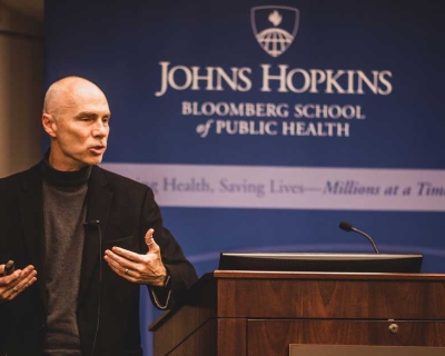 James Berger stands to the slide of a lecture, gestruring with his hands