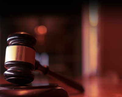 A gavel rests on a sounding block inside a court room