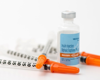 a vial of insulin with three syringes resting next to it