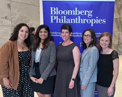 Members of the Gender Equity Unit Team pose in front of a Bloomberg Philanthropies sign at the Data for Health Partner Meeting 2023 in New York City.