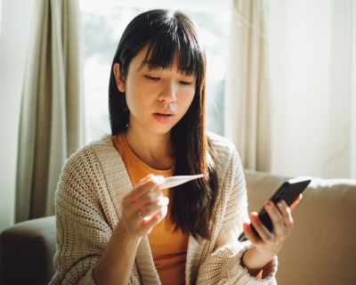 Woman in sunny living room reads thermometer results