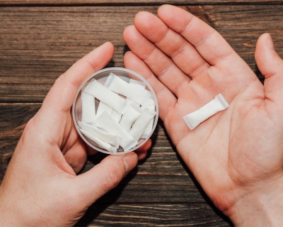 A person holds a container of nicotine pouches