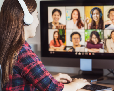 Woman in front of computer monitor displaying 8 people in an online course discussion