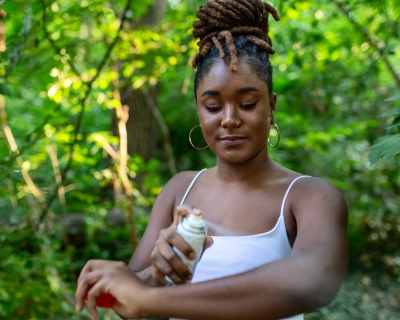 Woman applying insect repellent to her arms.